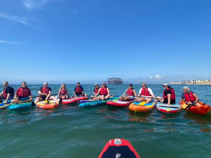 Paddle board group on Brighton sea sitting on boards